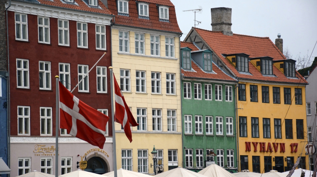 Dannebrog foran farverige bygninger i Nyhavn