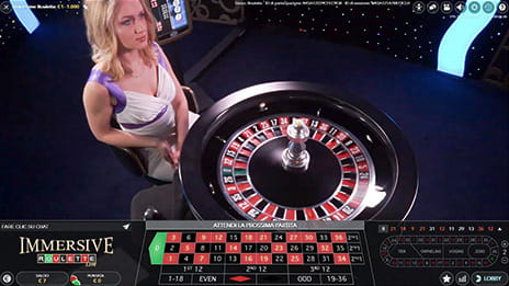 Un'avvenente croupier dell'Immersive Roulette Evolution Gaming accanto alla ruota.