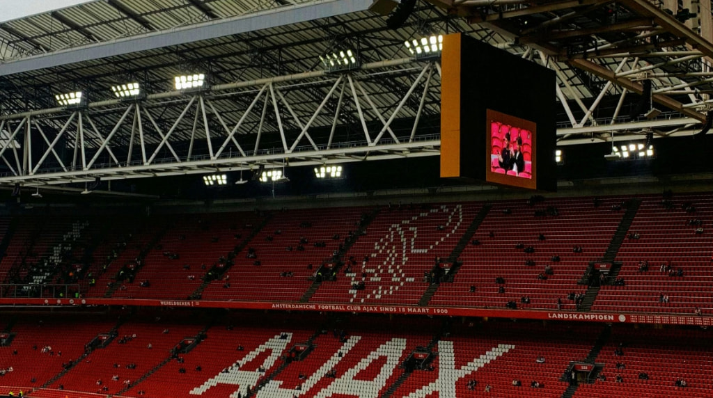 Vrijwel leeg Ajax stadion, het Ajax logo is te zien op de rode tribune