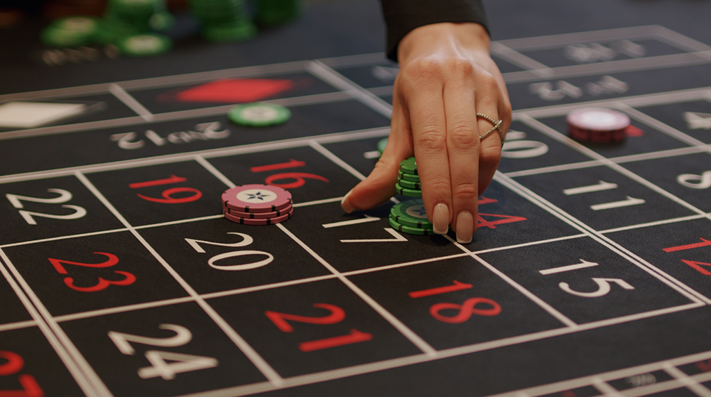 Vrouwenhand die casino chips plaatst op een casinotafel met speelkaarten.