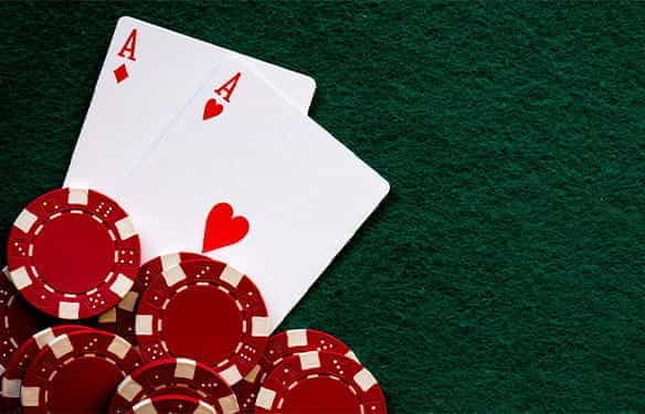 Two Aces of Hearts and red casino chips on a green felt background.