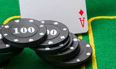 one card faceup on a playing table with a stack of casino chips next to it.
