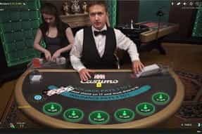 A female live dealer in a red dress at the Casumo blackjack table.