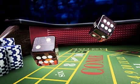 two dice in the air above a craps table in a land-based casino.