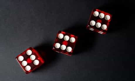 Three red dice on a black table.