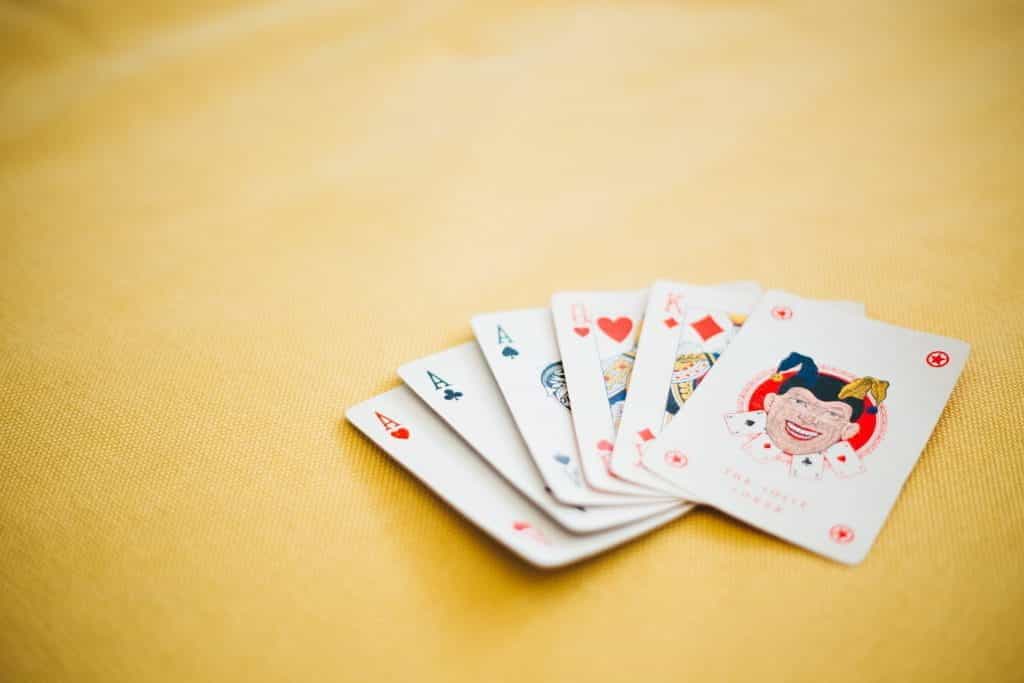 Playing cards on a table, with three Aces, a Queen, a King and a Joker showing.