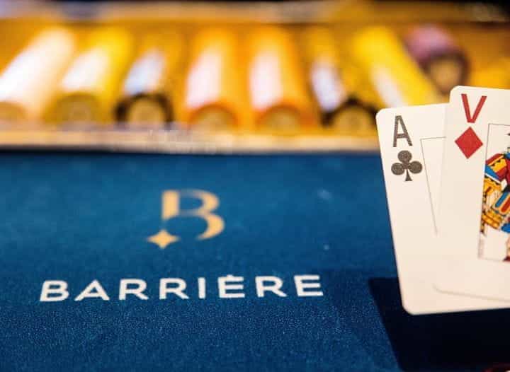 A felted poker table with the Barriere logo and cards.