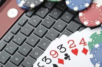 A pile of cards and poker chips stacked on a laptop's keyboard.
