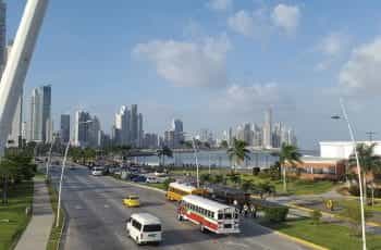 Alt Text: Panama City on a sunny day. You see a beach side street with tall skyscrapers in the background.
