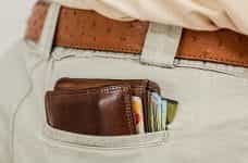 A stuffed wallet with credit cards in a pair of khaki pants.