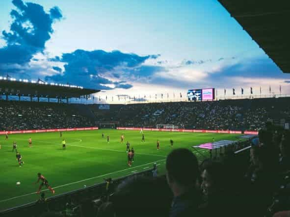 A football game in a large stadium as seen from the crowd.