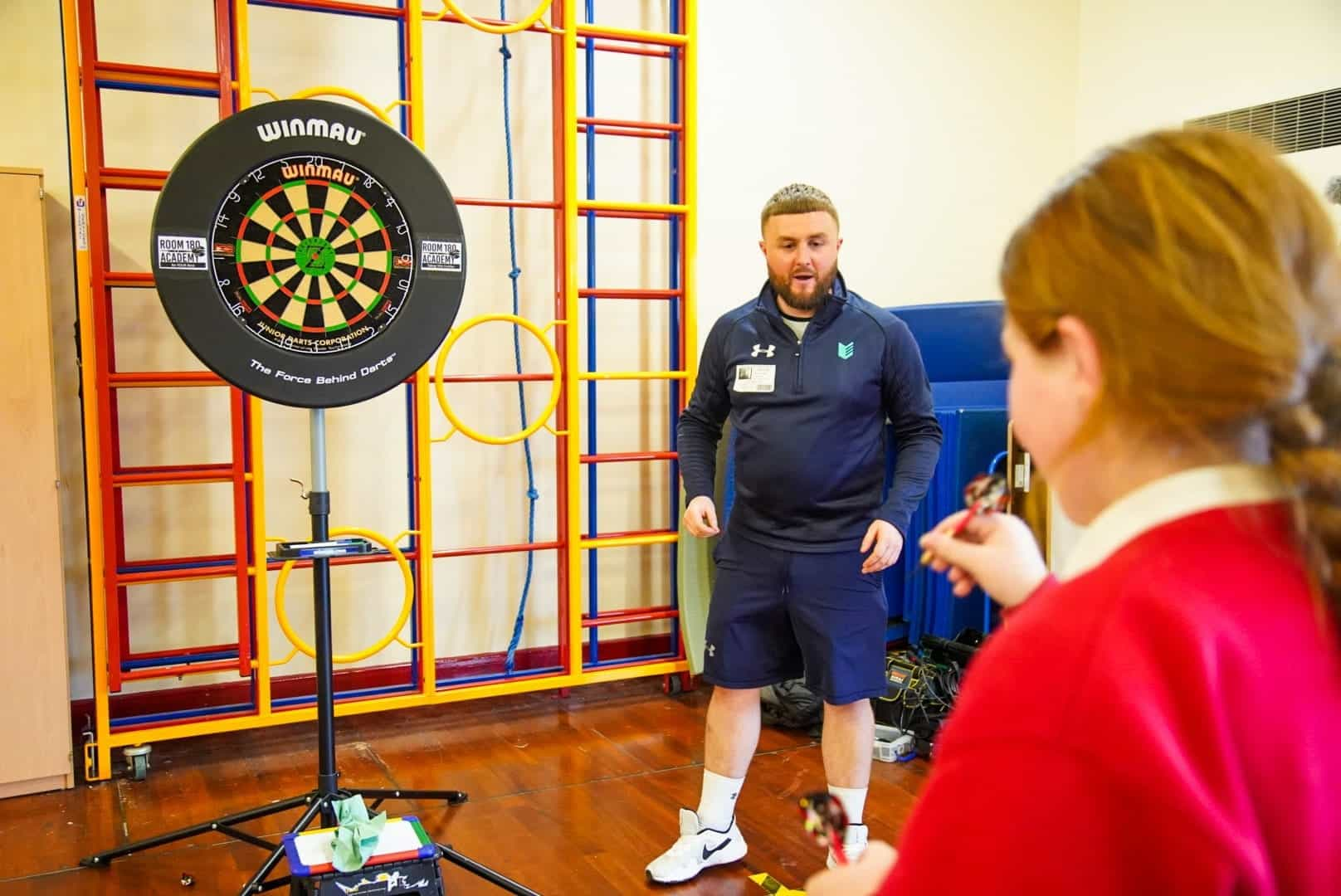 A schoolchild calculating maths whilst playing darts.