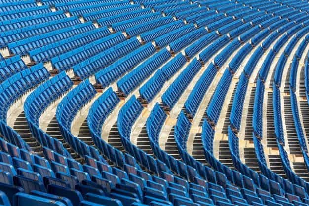 Multiple rows of blue seats at a large sports stadium.