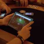 An individual plays online poker while sat at a traditional poker table.