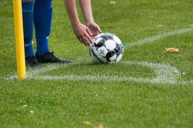 A footballer placing the ball next to a corner flag.