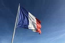 The French flag flying against a blue sky.