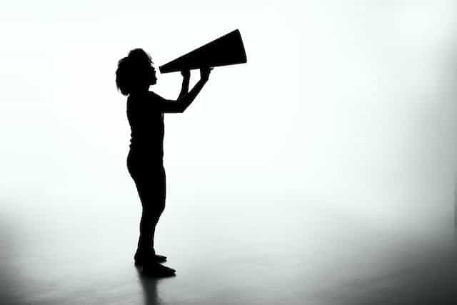 A silhouette of a woman holding a megaphone.