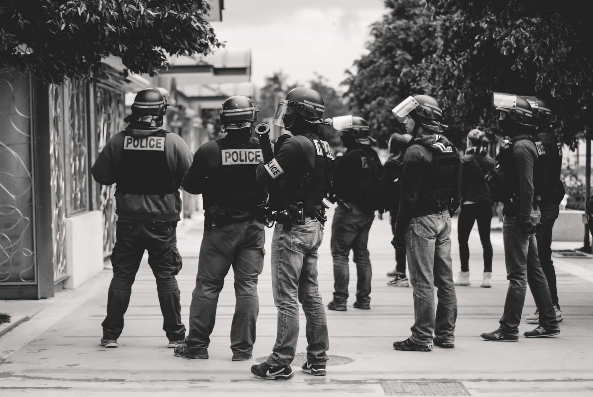 Black and white image of several police in protective gear standing at an event in Lyon, France.