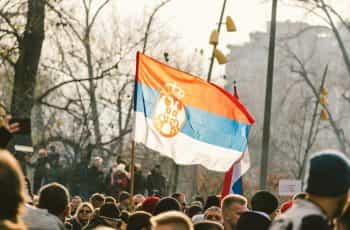 A crowd of people standing around a red, blue, and white flag.