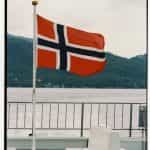 A flag hoisted on a deck near water.