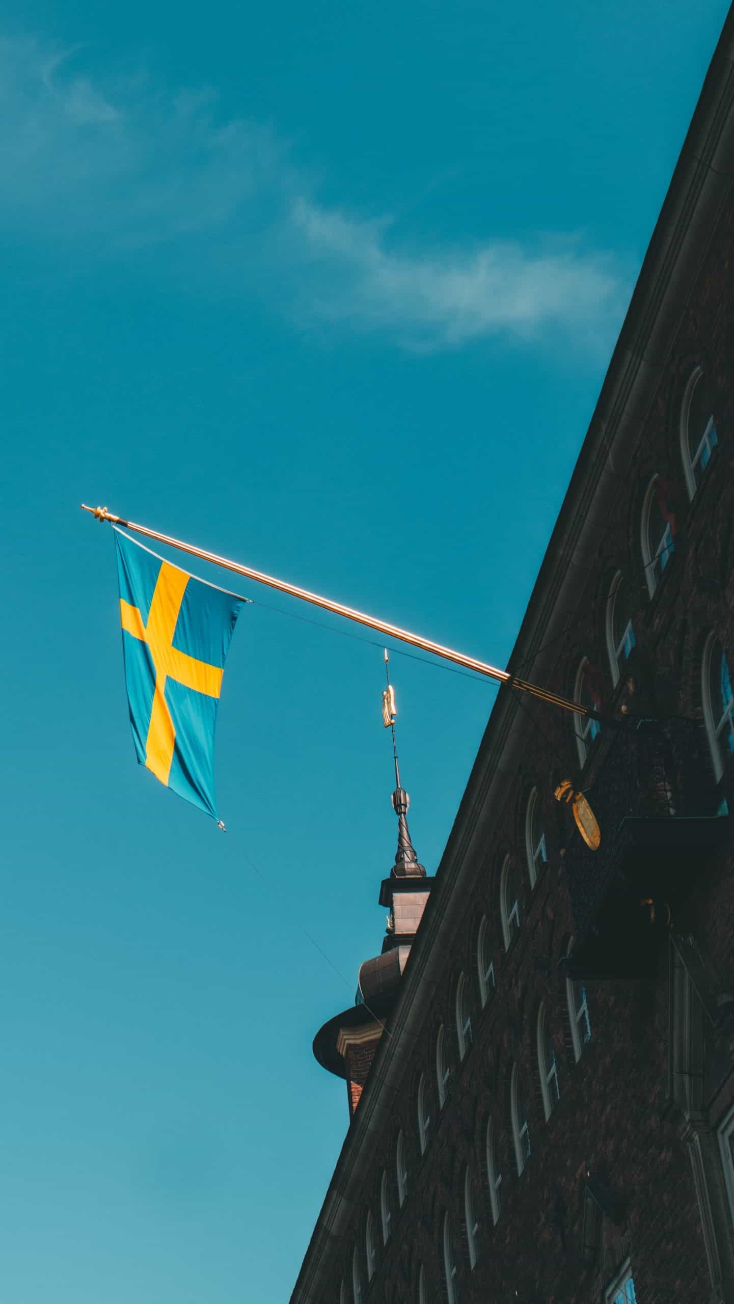 A blue and yellow flag hoisted from a building against a blue sky.