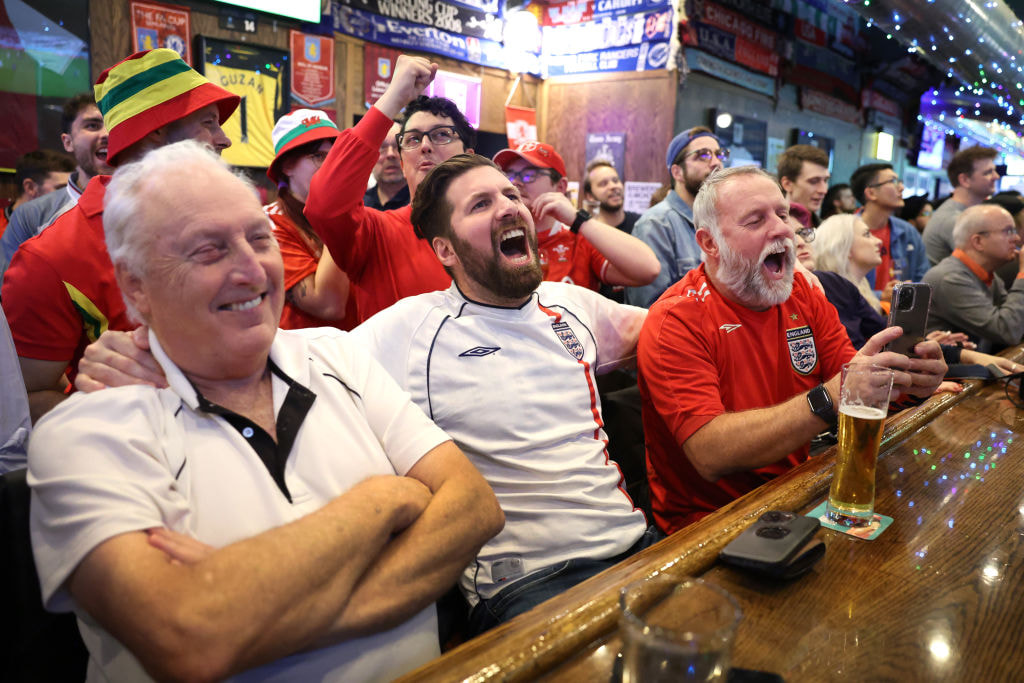 Football fans excitedly watching a game in a pub.