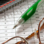 A Notebook, Pen, Glasses and a Piece of Paper with a Table