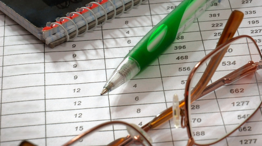 A Notebook, Pen, Glasses and a Piece of Paper with a Table