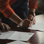 Two People at a Desk Signing Documents