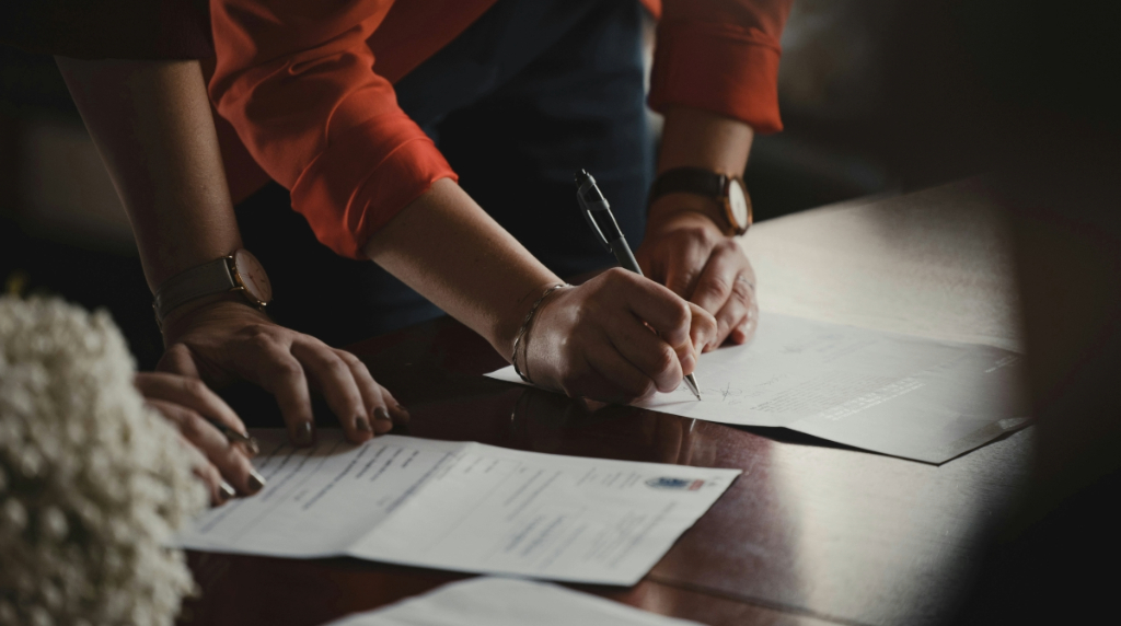 Two People at a Desk Signing Documents