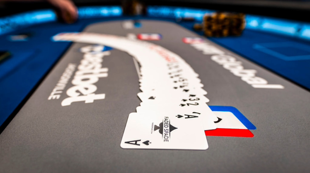 A deck of cards neatly spread in order across a poker table.