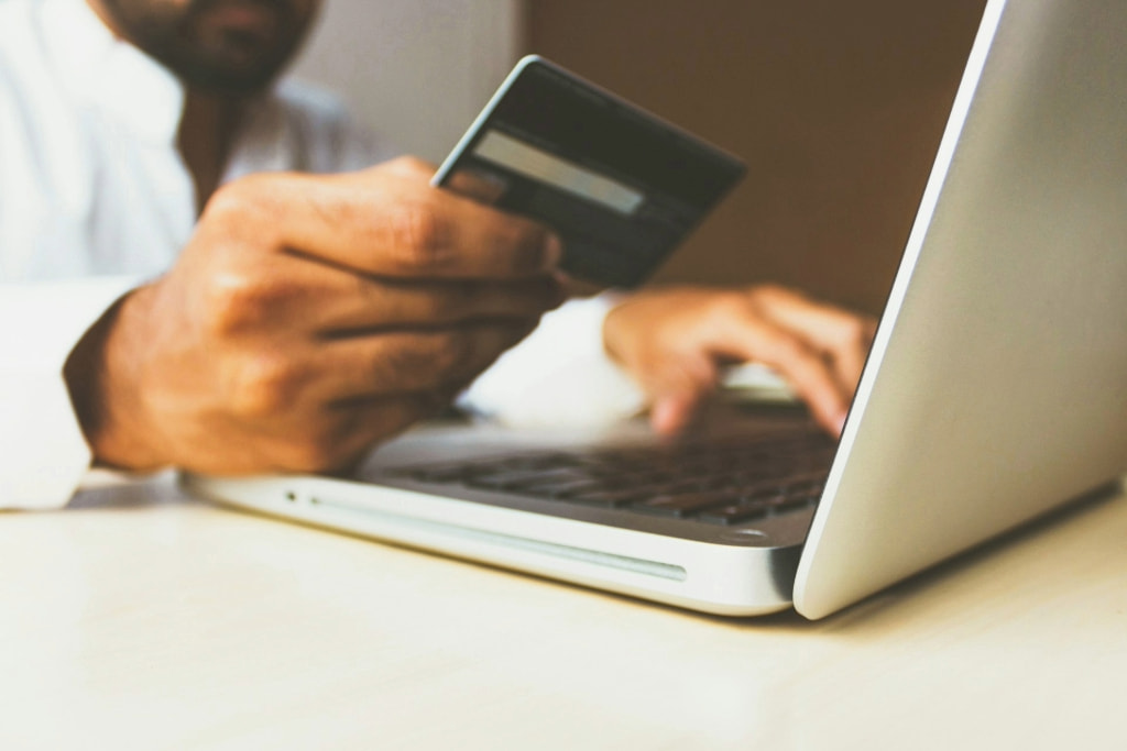 Person Using a Laptop and Holding a Debit Card