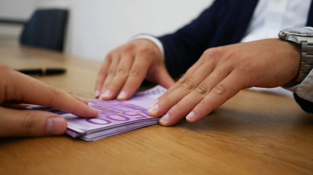 A Person Giving Someone a Pile of Banknotes